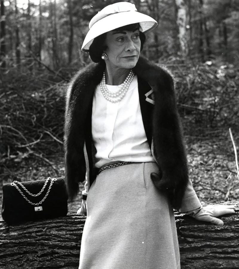 Coco Chanel modeling with a flap bag / Photo via Chanel