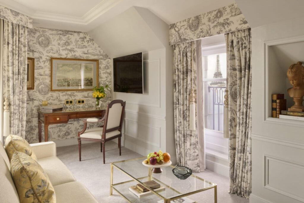 The style emphasizes a refined residential feel, combining Louis XVI furniture, classic Parisian architecture, soft tones, art pieces, and natural light. / Photo via Four Seasons George V