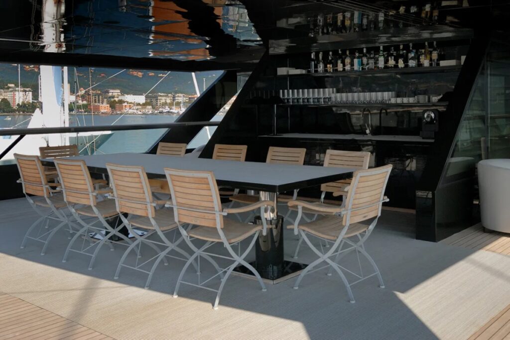 Design elements include subdued and rich colour palettes, dark green hull, continuous louvered windows, natural woods, marble finishes, custom Armani Casa furniture, and an interior aesthetic emphasizing calm luxury over flash. / Photo via Armani