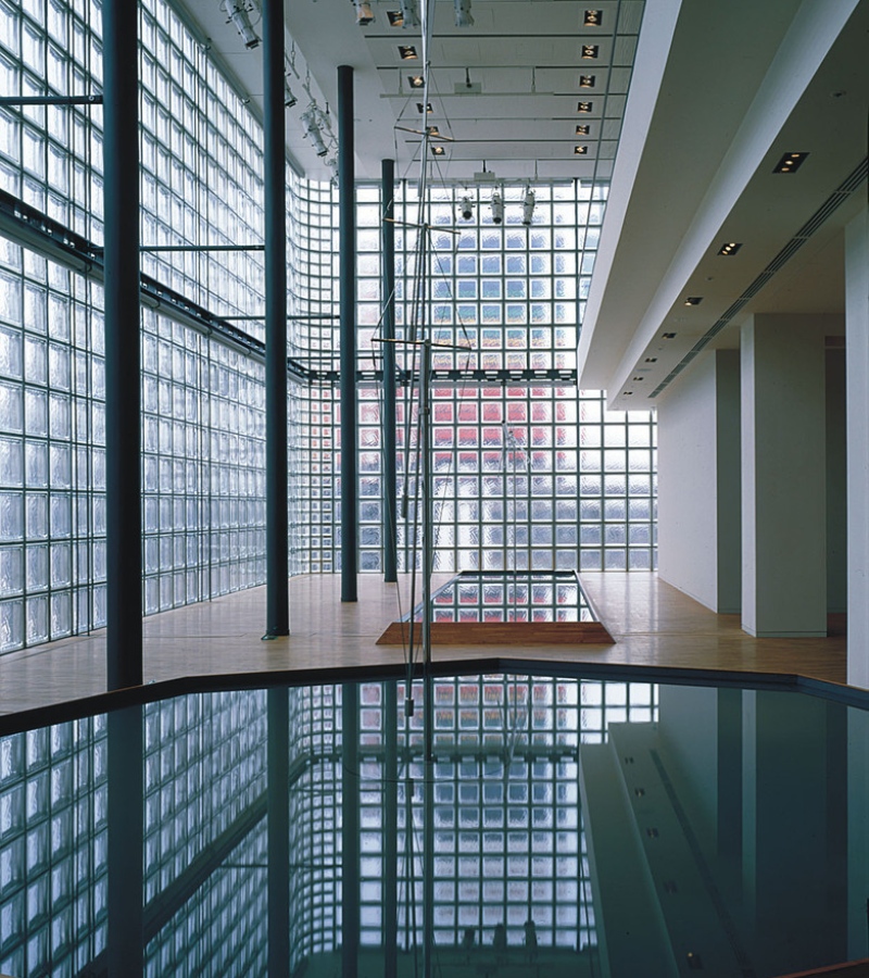The façade may appear monolithic, but the ground floor contrasts with clarity, revealing transparent glass bricks that invite passersby to glimpse Hermès creations. / Photo Hermes Tokyo