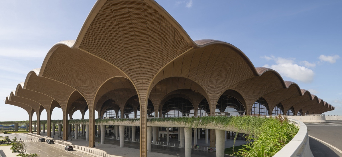 These panels serve both aesthetic and functional roles, filtering daylight to create a comfortable interior environment while referencing traditional Cambodian basket weaving. / Photo via Foster + Partners
